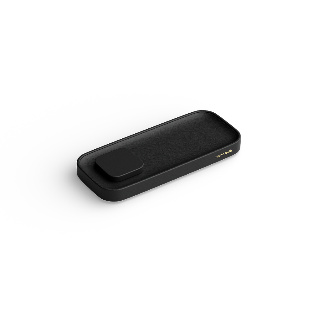A sleek black rectangular charging valet with rounded corners and a small raised button on top, shown at an angle on a clean white background. The brand name  Twelve South is printed in small gold lettering on the right side.