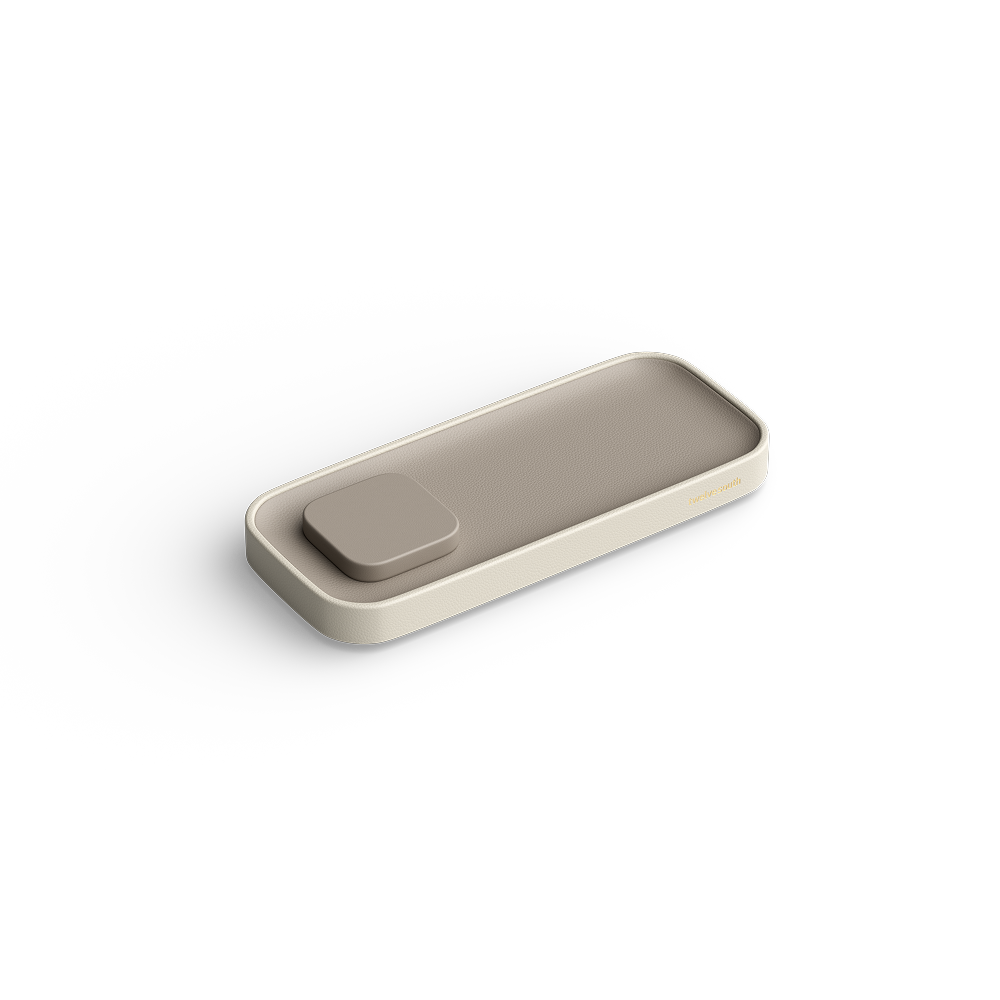 A minimalist rectangular tray with rounded corners and a small square lid on top, shown in a warm beige color on a clean white background.