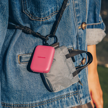 Pink PowerClip attached to a gray bag on a person wearing a blue denim jacket.