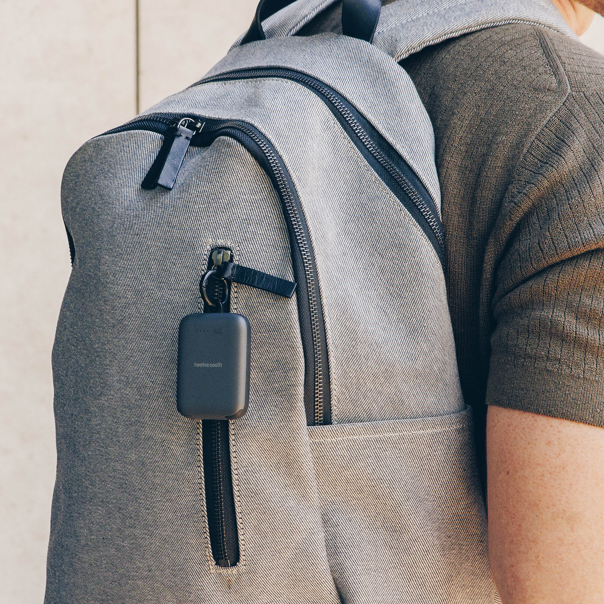 Person wearing a gray backpack with a black device attached to it.