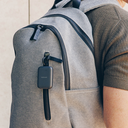 Person wearing a gray backpack with a black device attached to it.