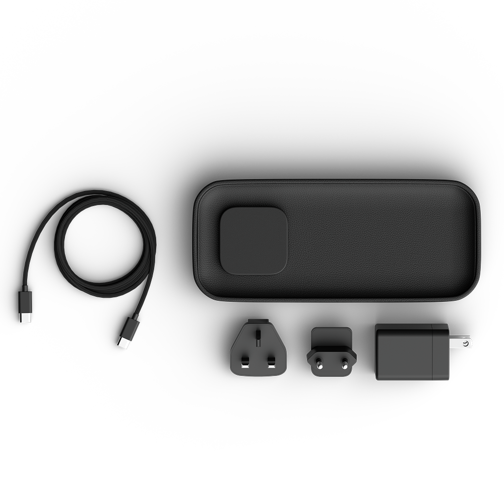 A black charging valet set shown on a clean white background, including the main rectangular power bank, a coiled USB-C cable, two plug adapters, and a wall charger.