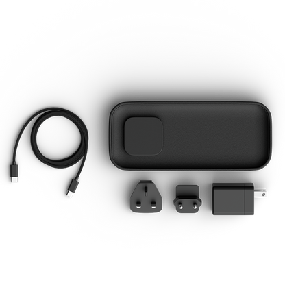 A black charging valet set shown on a clean white background, including the main rectangular power bank, a coiled USB-C cable, two plug adapters, and a wall charger.