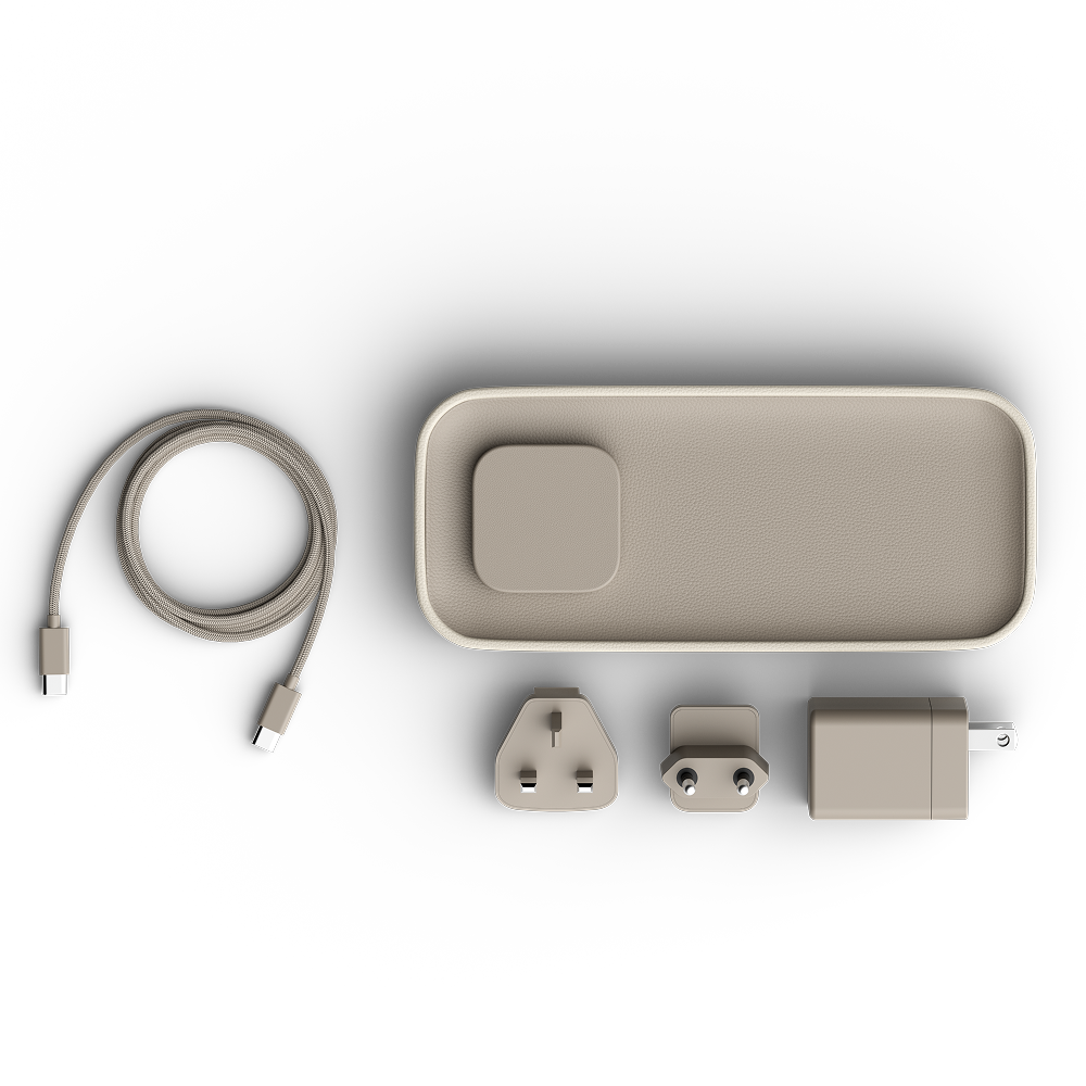 A minimalist travel power bank set in a warm taupe-beige color, featuring a coiled USB-C cable, a rectangular power bank with a built-in square connector, a UK three-pin plug, a European two-pin plug, and a wall charger adapter, all arranged neatly on a white background.